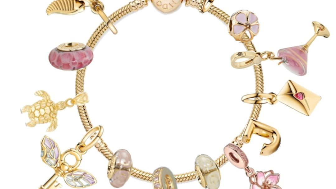 Gold charm bracelet with various charms on a white background